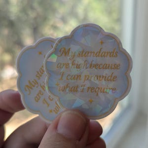 May include: Two cloud-shaped stickers with the text "My standards are high because I can provide what I require" in gold lettering. The stickers have a light blue background with a geometric design and gold stars.