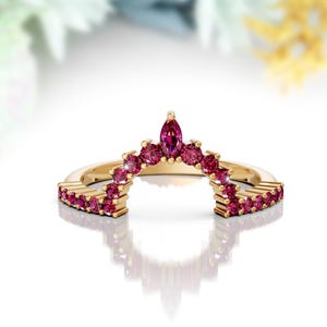 Peut inclure: Une bague en or avec un design incurvé serti de petites pierres précieuses roses. La bague est conçue pour être portée comme un rehausseur de bande de mariage.