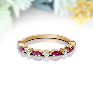 May include: A gold band ring with alternating marquise-shaped ruby and round diamonds.