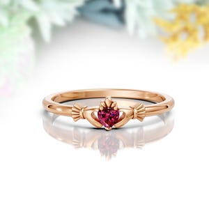 May include: A rose gold ring featuring a heart-shaped pink gemstone set in a Celtic knot design.