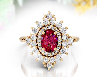 May include: A gold ring with an oval ruby centre stone, encircled by a halo of small diamonds. Further diamonds create a starburst pattern around the centre. The ring is set on a gold band, offering a classic and elegant appearance.
