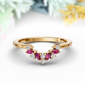 Peut inclure: Une bague dorée avec un design incurvé. La bague présente des pierres précieuses roses foncées de taille marquise et de petites pierres précieuses claires et rondes. Les pierres précieuses sont serties dans un motif décoratif sur le dessus de la bague.