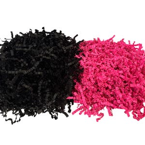 Pode incluir: Duas pilhas de papel picado, uma preta e outra rosa brilhante, estão lado a lado sobre um fundo branco. O papel é cortado em tiras finas, criando uma aparência texturizada e volumosa. Este enchimento decorativo é frequentemente usado para embalagens de presente.