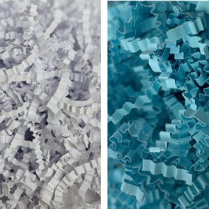 Pode incluir: Close-up de duas secções de papel picado. Uma secção é branca, a outra é azul claro. O papel é cortado em tiras finas e onduladas, criando uma aparência texturizada e em camadas. Ideal para embalagem e artesanato.