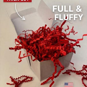 Può includere: Una scatola bianca piena di carta crespa rossa a taglio spesso. Le parole "FULL & FLUFFY" sono visualizzate sopra la scatola. Il testo "THICK CUT" è in una casella rossa. La bandiera americana e "MADE IN USA" sono in basso a destra.