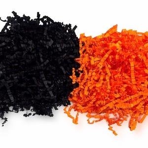 Pode incluir: Duas pilhas de papel picado, uma preta e outra laranja brilhante, contra um fundo branco. O papel é cortado em tiras finas, criando uma aparência texturizada. Ideal para embalagens de presente ou fins decorativos.