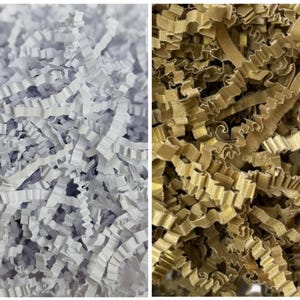 Pode incluir: Close-up de duas pilhas de papel de seda. Uma pilha é branca, a outra é dourada. O papel é triturado em tiras finas e onduladas, criando um enchimento texturizado e decorativo para caixas de presente e embalagens.