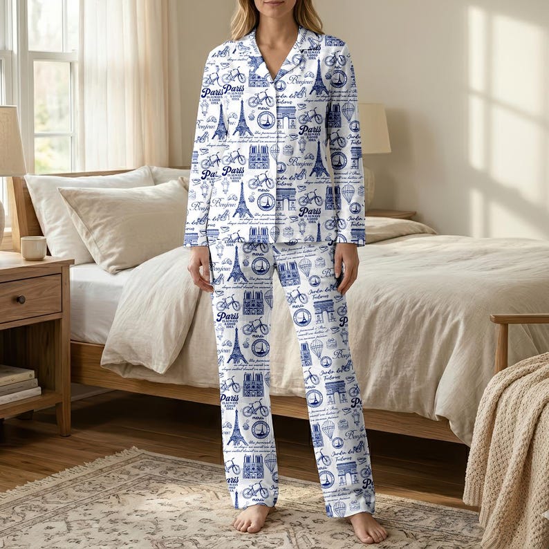 以下が含まれることがあります： パリをテーマにした青い模様の白いパジャマセット。デザインには、エッフェル塔、自転車、そして「パリ」という言葉が含まれています。長袖のトップスは襟付きで、パンツはゆったりとしたフィット感です。