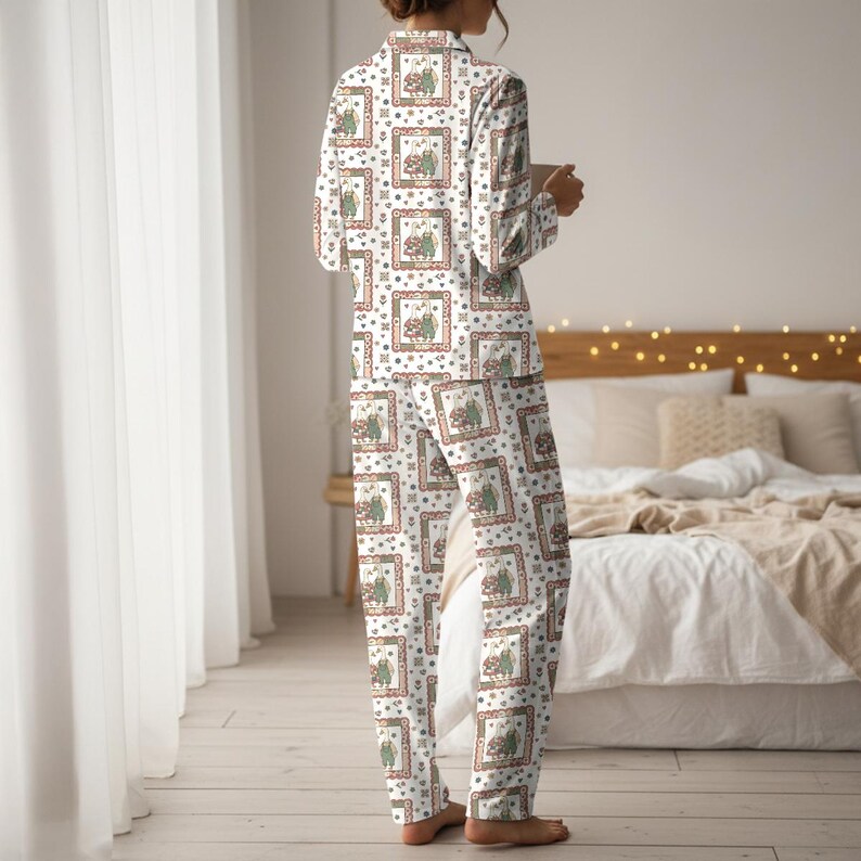 May include: White pajama set with a repeating pattern of framed illustrations in red, green, and brown. The long-sleeved top and pants are made of a soft fabric. The pajama set is designed for comfort and relaxation.