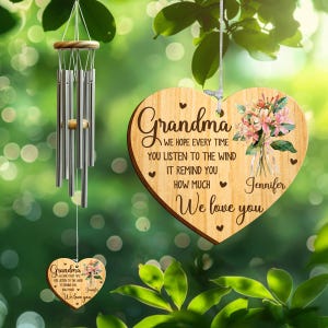 May include: A wooden heart-shaped wind chime with the word "Grandma" and a floral design. The text reads "We hope every time you listen to the wind it remind you how much we love you, Jennifer." A smaller version hangs below.