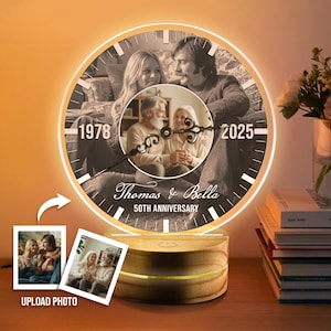 May include: A personalized illuminated clock with a wooden base. The clock face features a black and white photo of a couple, with the years 1978 and 2025 displayed. The clock is labeled "Thomas & Bella 50th Anniversary."