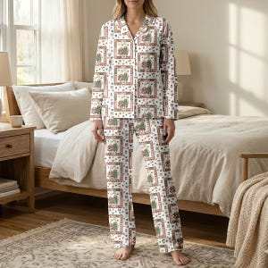 May include: White pajama set with a repeating pattern of framed illustrations, hearts, and small floral designs. The long-sleeved top has a collared neckline and button closure. The matching pants have a relaxed fit. The set is made of a soft, comfortable material.