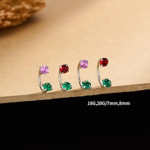 May include: Four silver nose rings with coloured gemstones. Each ring has a curved design with a coloured gem at the top and bottom. The gemstones are pink, red, and green. The text "18G,20G/7mm,8mm" is visible.