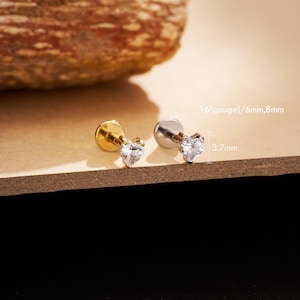 May include: Two heart-shaped stud earrings. One is gold-toned, the other silver-toned. Each earring features a clear, sparkling heart-shaped stone. The text on the image reads: 1.6 (gauge)/6mm,8mm and 3.7mm.