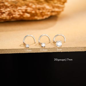 May include: Three silver nose studs with clear cubic zirconia stones. Sizes are 1.5mm, 2.5mm, and 3mm. The gauge is 20 and the length is 7mm.