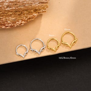 May include: A collection of three metal nose rings with a deer antler design. The rings are silver and gold in color, with sizes of 8mm and 10mm. The text "16G/8mm,10mm" is visible.