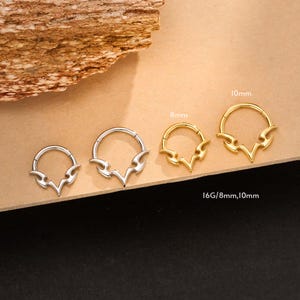 May include: A collection of three hoop earrings with a tribal flame design. The earrings are available in silver and gold tones, with sizes 8mm and 10mm. The earrings are displayed on a neutral surface.