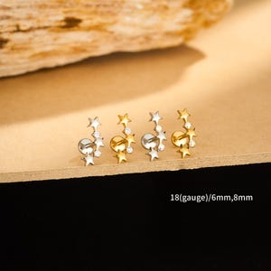 May include: Four pairs of star-shaped earrings in gold and silver tones. Each earring features a cluster of small stars and clear gemstones. The text "18(gauge)/6mm,8mm" is visible.
