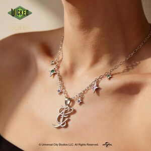 May include: A silver necklace with a pendant featuring the letter "E" in a stylized script. The necklace has small star-shaped charms with green, purple, and pink accents. The image includes the text "WICKED" and "OUFER".