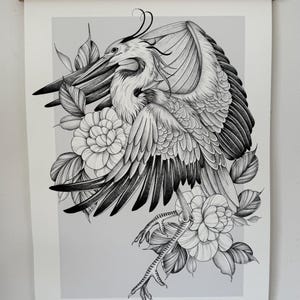 May include: Black and white illustration of a heron with outstretched wings, surrounded by flowers and leaves. The artwork is displayed on a white paper, held by a wooden frame. The artist's name is visible at the bottom.