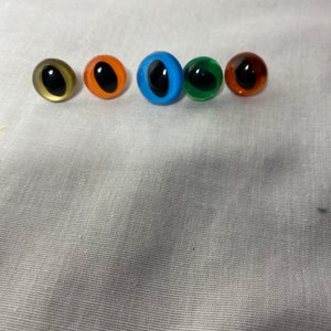 May include: Five plastic safety eyes for crafts, in various colors: gold, orange, blue, green, and brown.