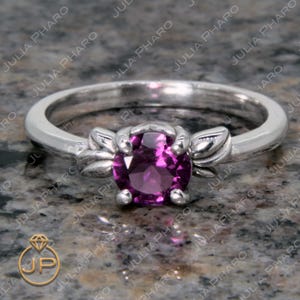 May include: A silver ring with a purple gemstone set in a floral design.