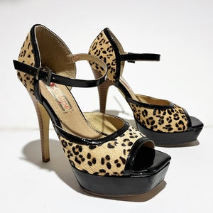 May include: A pair of black and leopard print platform heels with an ankle strap. The heels are about 5 inches tall and have a platform that is about 1 inch tall.