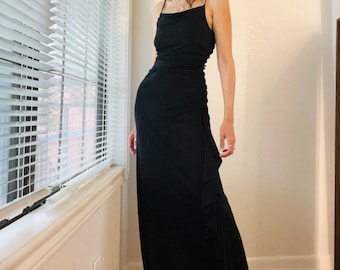 Può includere: Un abito maxi nero con un corpetto drappeggiato e una gonna fluida. L'abito ha un design semplice ed elegante ed è perfetto per un'occasione formale.