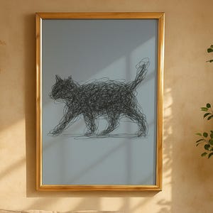 Könnte beinhalten: Gerahmtes Kunstwerk mit einer Illustration einer schwarzen Katze. Die Katze ist in einem Kritzelstil dargestellt, vor einem hellgrauen Hintergrund in einem goldenen Rahmen. Das Kunstwerk hängt über einem beigen Sofa in einem Wohnzimmer.