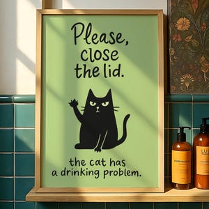 May include: A framed print with a light green background and a black cat illustration. The text reads "Please, close the lid. the cat has a drinking problem." Three brown bottles with black labels sit on a wooden shelf below the print.