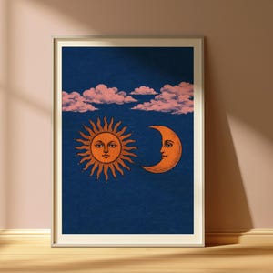 May include: Framed art print with a celestial theme. The image shows an orange sun and crescent moon with faces, set against a dark blue backdrop with pink clouds. The print is in a white frame, suitable for wall decor.