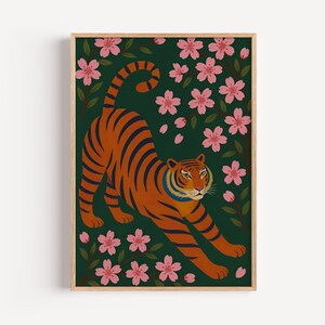 May include: A framed art print featuring an orange tiger with black stripes stretching among pink cherry blossoms and green leaves against a dark green background. The artwork has a minimalist, illustrative style.