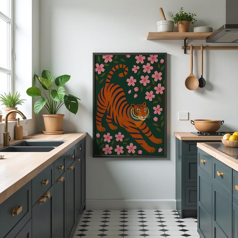 May include: A framed art print featuring an orange tiger with black stripes, set against a dark green background with pink cherry blossoms. The tiger is in a stretching pose. The artwork is displayed in a modern kitchen setting.