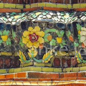 May include: Close-up of a section of a temple wall with intricate mosaic tilework. The design features floral patterns with yellow, white, and red flowers, green leaves, and geometric patterns in orange, green, and white.