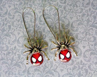 Puede incluir: Un par de pendientes colgantes con diseño de araña. Cada pendiente tiene una cara de araña roja y blanca, un cuerpo negro y múltiples patas. Los pendientes son de metal y tienen un gancho largo y curvado.