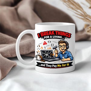 Könnte beinhalten: Weiße Keramiktasse mit dem Text "I Break Things for a Living...and They Pay Me for It". Die Tasse zeigt eine Cartoon-Illustration einer Person mit Kopfhörern, Brille und Hammer, die einen Laptop kaputt macht.