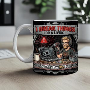 Könnte beinhalten: Weiße Keramik-Tasse mit schwarzem Design. Der Text lautet: „Ich repariere Dinge für meinen Lebensunterhalt... und sie bezahlen mich dafür“. Das Design zeigt eine Person mit Kopfhörern, einem Bohrer und einem kaputten Laptop.