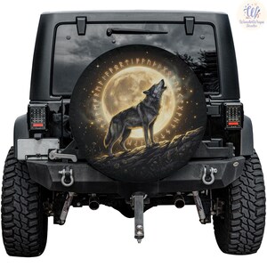 May include: A black Jeep with a spare tire cover featuring a howling wolf against a full moon. The design includes a ring of runes and a starry night sky. The spare tire cover is round.