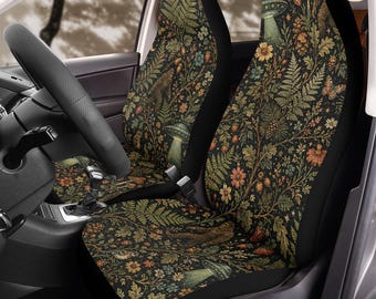 May include: A pair of car seat covers featuring a dark background with a dense botanical pattern of green ferns, oak leaves, orange flowers, pinecones, and butterflies, interspersed with illustrations of Bigfoot and flying saucers.