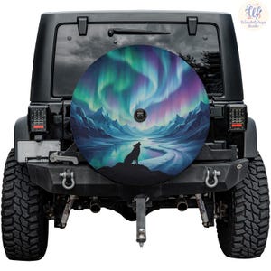 May include: A spare tire cover featuring a vibrant illustration of the Northern Lights. The design showcases a wolf silhouette howling at the moon, set against a backdrop of mountains and a reflective body of water. The color palette includes shades of blue, green, purple, and black.