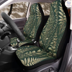 Könnte beinhalten: Autositzbezüge mit einem botanischen Design. Die Bezüge zeigen einen dunkelgrünen Hintergrund mit einem Muster aus beigen und goldfarbenen Farnen, Blättern und Wildblumen. Das Design bedeckt den gesamten Sitz, einschließlich der Kopfstütze und der Sitzfläche. Der Innenraum des Autos ist sichtbar.
