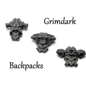 May include: Three gray Grimdark backpacks are displayed against a white background. The backpacks have intricate mechanical details, including tubes, vents, and geometric shapes. The word "Grimdark" is written above the backpacks, and the word "Backpacks" is written below.