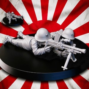 May include: A detailed miniature of two soldiers in a prone firing position, holding a machine gun. The figures are gray, set against a backdrop of a Japanese flag with red and white stripes. A smaller figure is in the background.