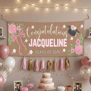 Puede incluir: Una pancarta de graduación con las palabras "Felicidades Jacqueline Clase de 2026" en blanco y rosa. La pancarta está decorada con flores rosas, un birrete y un lazo rosa. Una tarta de tres pisos, globos y borlas están frente a la pancarta.