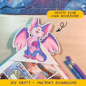 Può includere: Un segnalibro colorato con una creatura dei cartoni animati alata, nei toni del blu, rosa e viola. Il segnalibro è posizionato su una pagina di fumetti. Il testo sull'immagine recita "CREATE YOUR OWN BOOKMARK" e "DIY CRAFT • INSTANT DOWNLOAD".