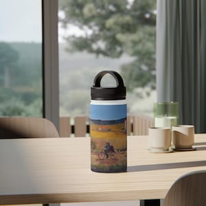 May include: A stainless steel water bottle with a black handle and lid. The bottle features a landscape painting of two people riding bicycles on a dirt road, with a blue sky and yellow fields in the background.
