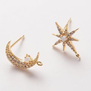 May include: Two gold-tone earring charms, one shaped like a crescent moon and the other like a star. Both charms are adorned with clear rhinestones and have a small loop at the top for attaching to earrings.