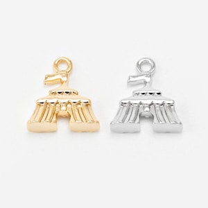 May include: Two metal charms shaped like circus tents, one finished in a polished gold tone and the other in a bright silver tone. Each charm features a small circular loop at the top for attachment, with vertical ridged detailing.