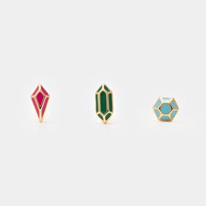 May include: Three gold-colored stud earrings with colorful geometric designs. One earring is a red diamond shape, another is a green emerald shape, and the third is a blue and gold hexagon shape. The earrings are displayed on a white background.