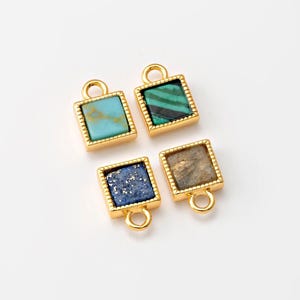 May include: Four gold-toned square charms with different colored gemstone inlays. The charms have a loop at the top for attaching to jewelry.